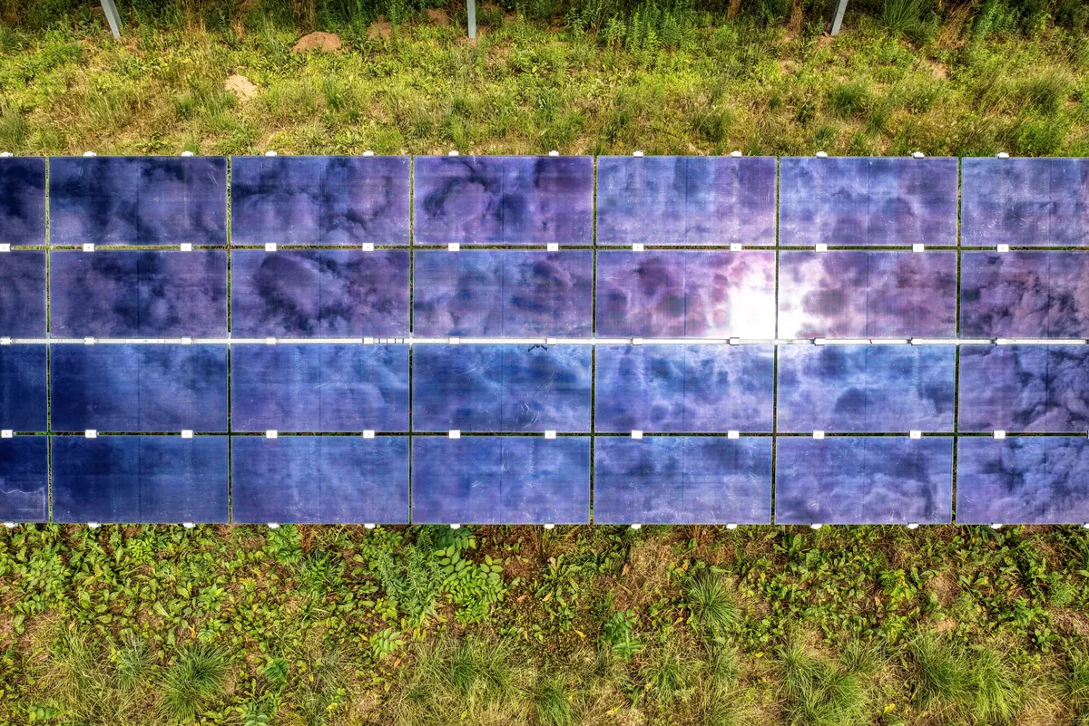Aerial view of a ground-mounted solar array in a grass field