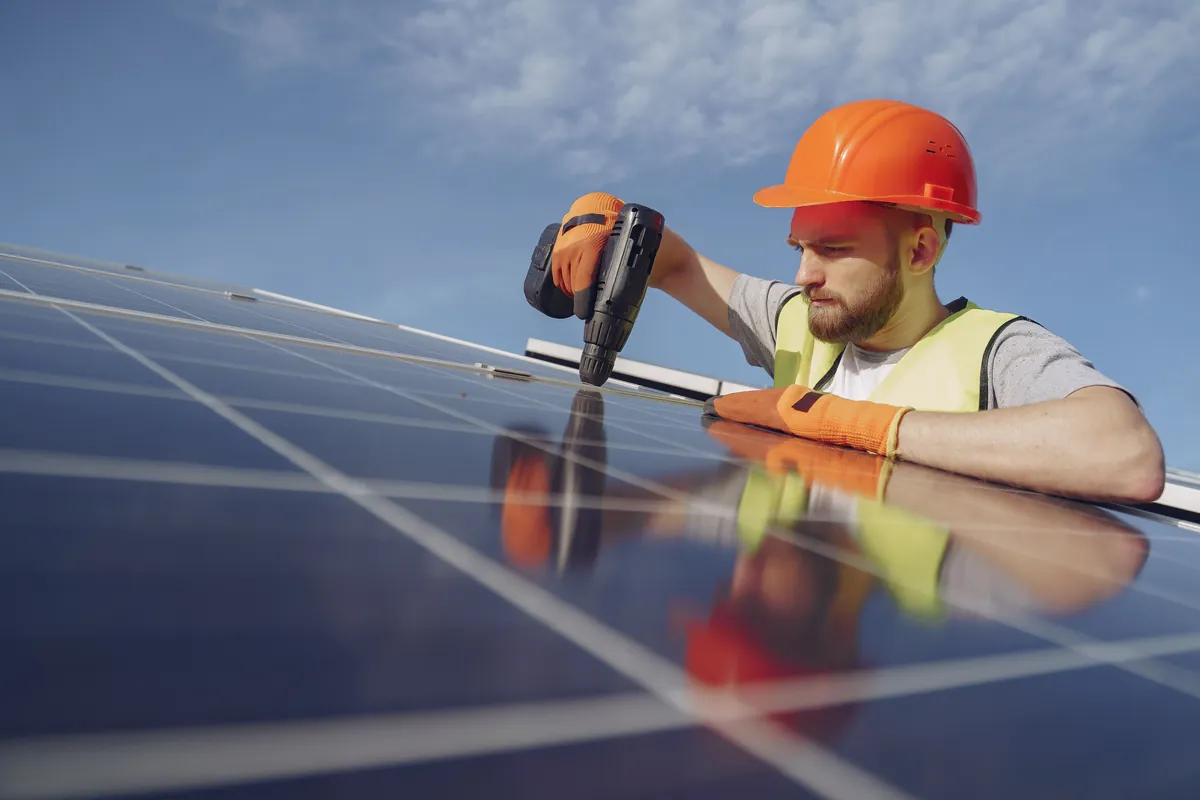 Installer fitting a solar panel on a roof, close up