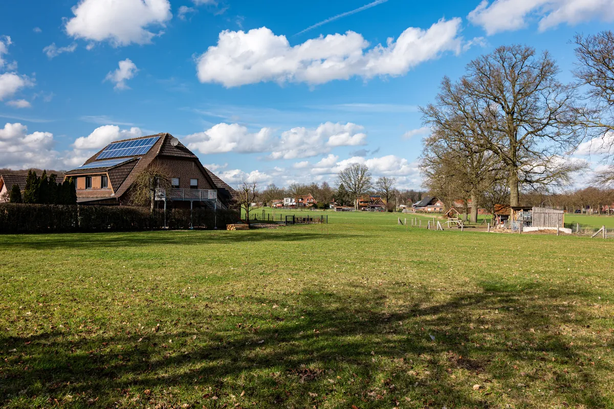Rural house with solar panels on the roof, surrounded by open fields